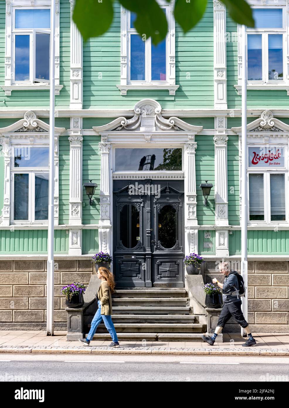 La gente pasa por el edificio de madera verde claro y blanco FRU Lundgreen Bar, Trondheim, Noruega Foto de stock