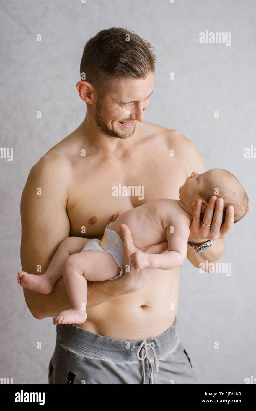 Un padre feliz sostiene a un bebé recién nacido en sus brazos Foto de stock