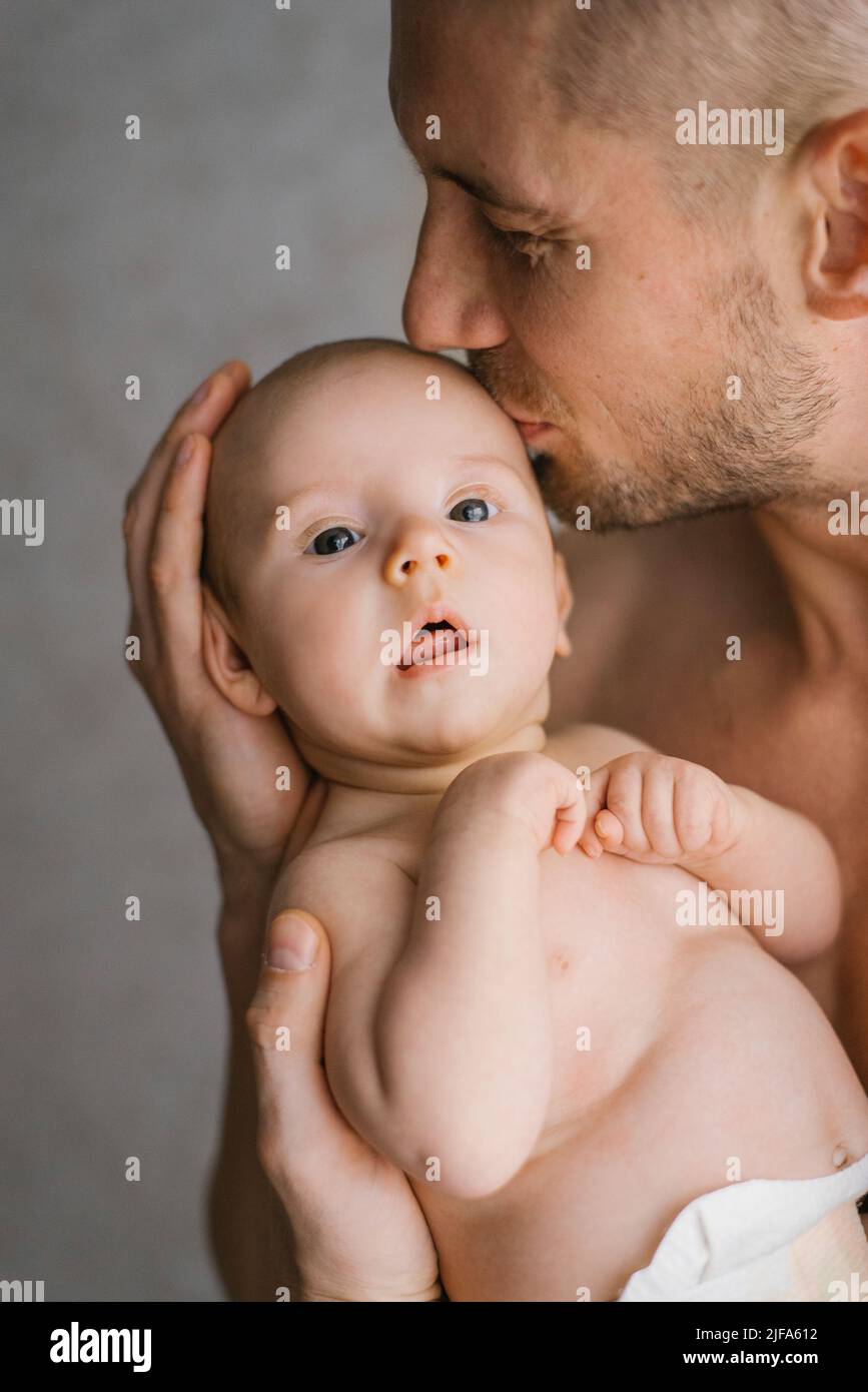 Padre sosteniendo a su bebé recién nacido en las manos. Padre besando a su bebé Foto de stock