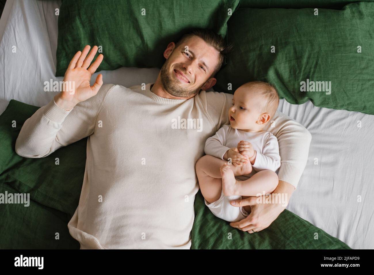 El joven padre caucásico juega y se ríe con su hijo en la cama, en el dormitorio, familia feliz Foto de stock
