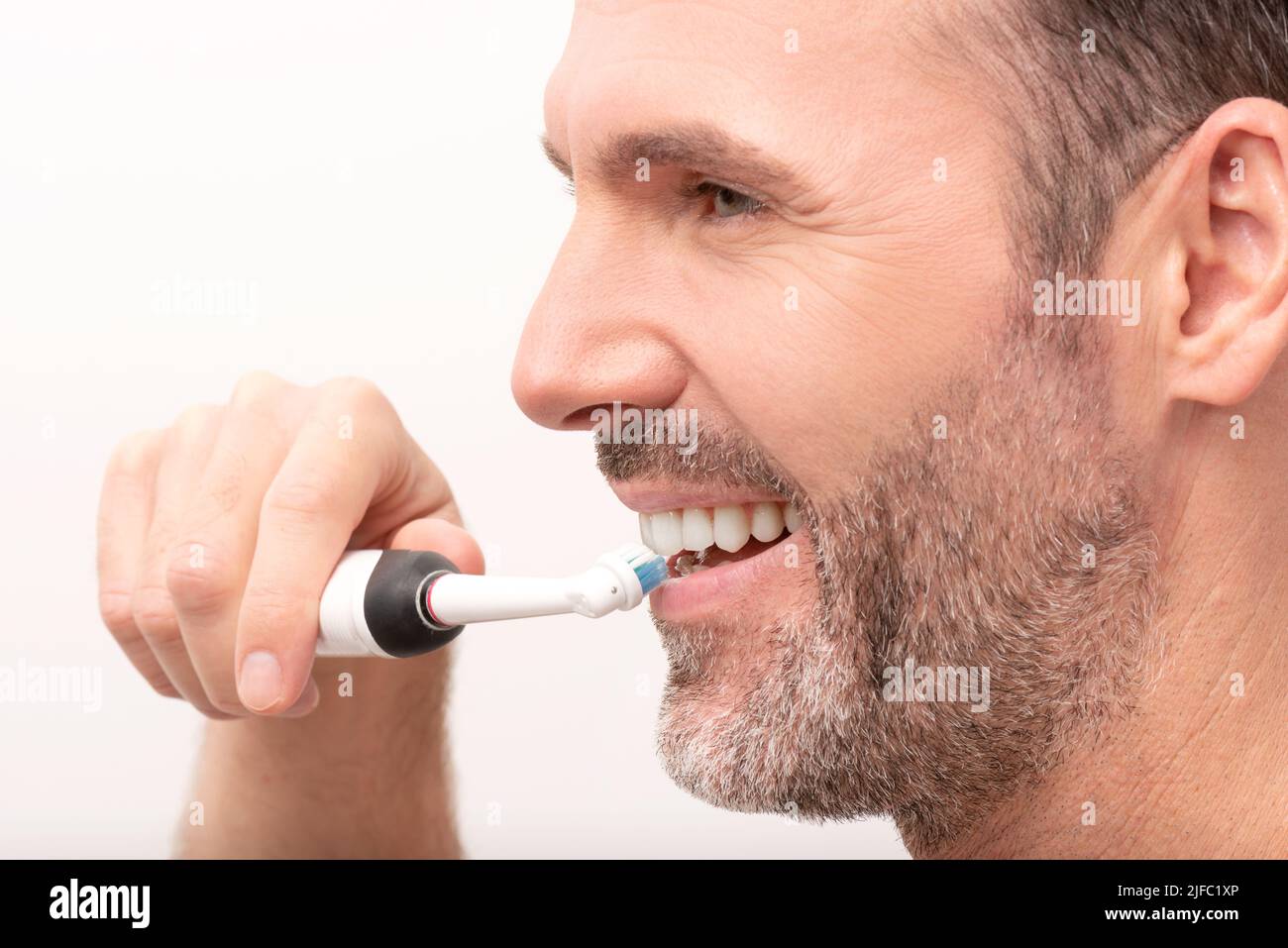 Hombre usando un cepillo de dientes eléctrico. Concepto de cuidado dental Foto de stock