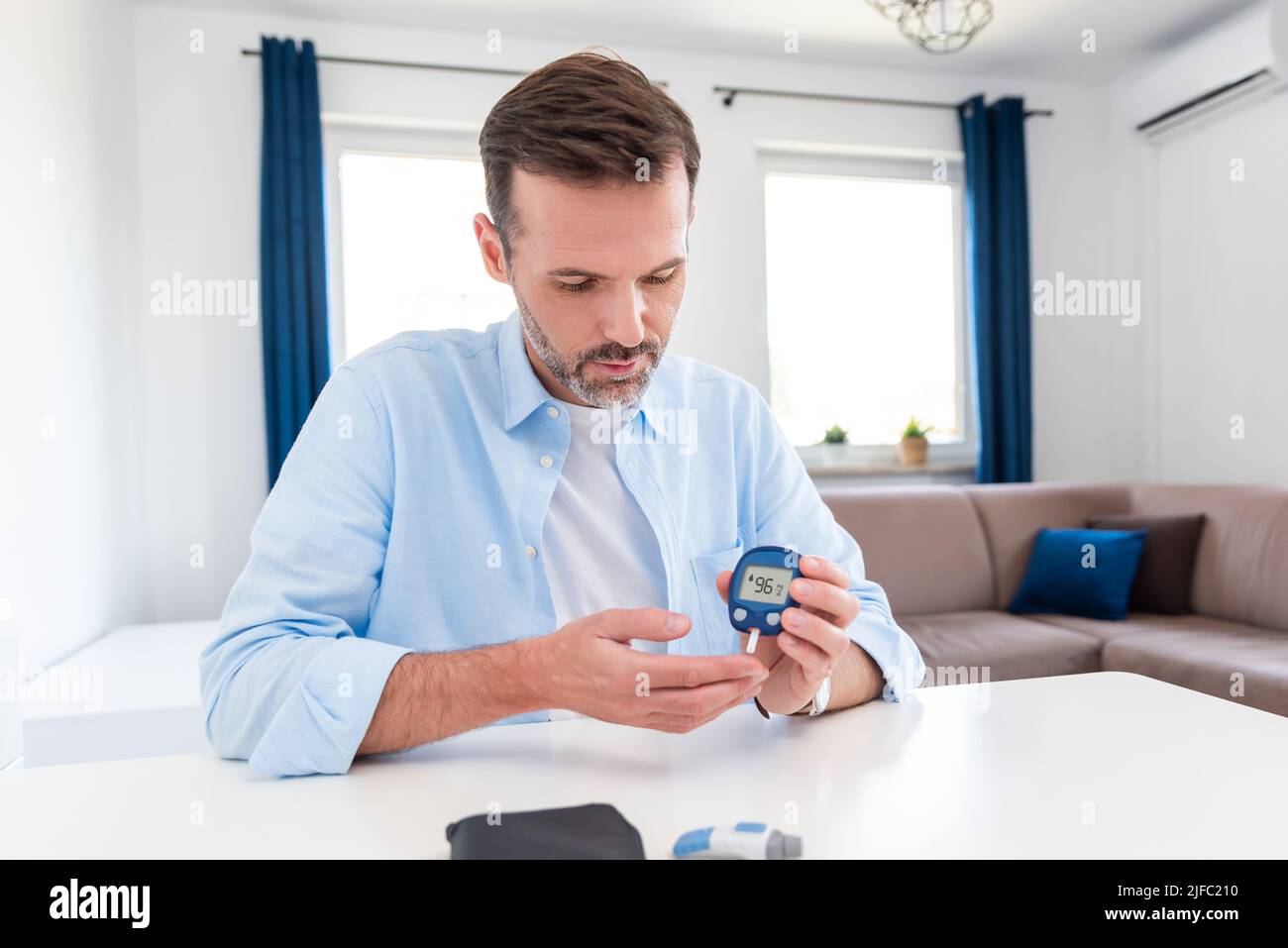 El hombre mide su azúcar en la sangre. Glucómetro, prueba de muestras de sangre, concepto de diabetes. Foto de stock