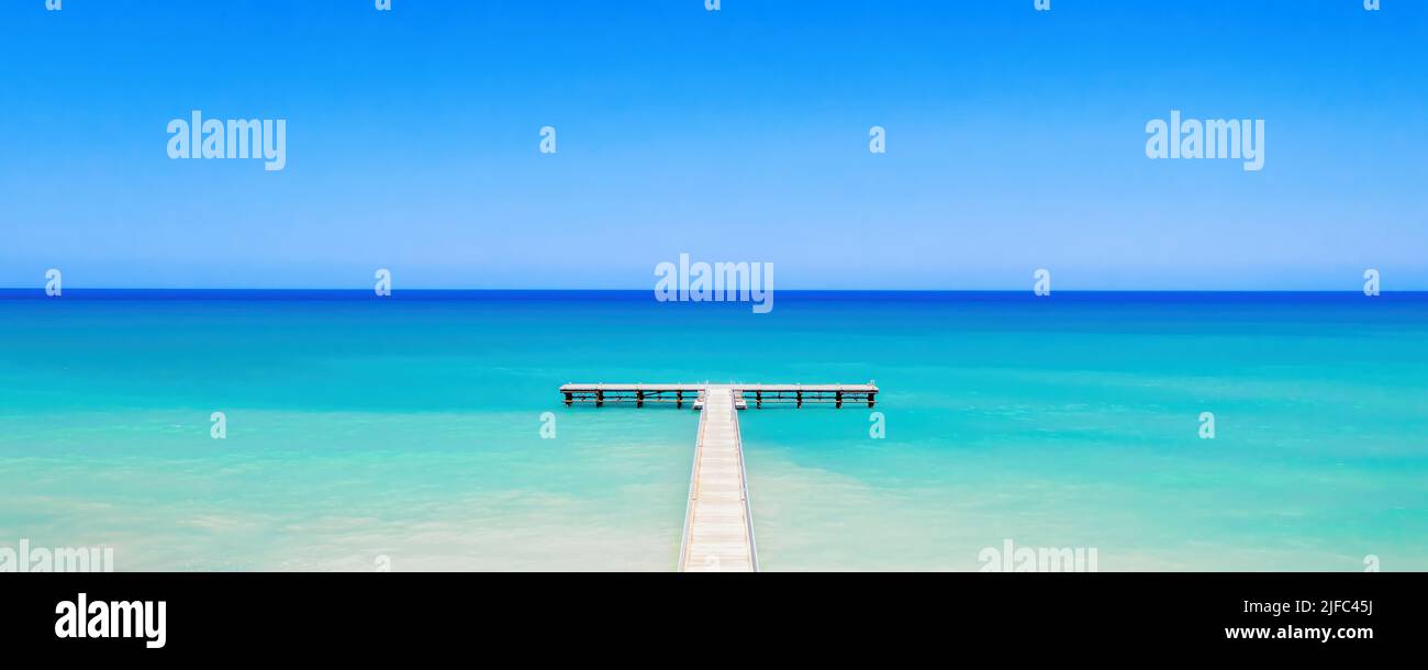 Muelle de madera blanca sobre aguas de mar de color turquesa brillante. Panorama de la costa tropical de la isla Foto de stock