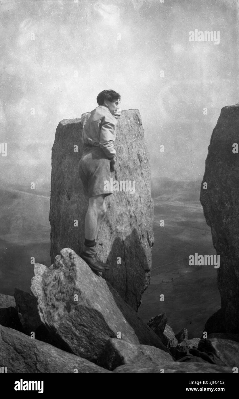 1952, histórico, un hombre caminante en la cima de Tryfan, Snowdonia, Gales del Norte, Reino Unido, de pie en una cornisa por uno de los monolitos gemelos de Adán y Eva (Sion a Sian en Wlesh) un par de rocas de tres metros de altura. Foto de stock
