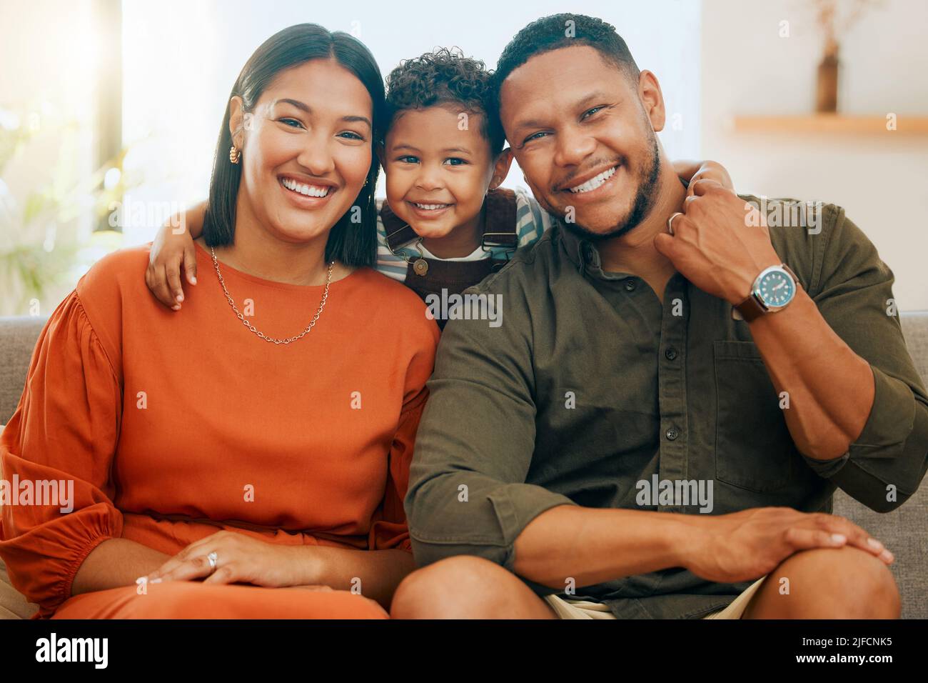 Una feliz familia de tres personas que se relajan juntos en el salón. Familia negra cariñosa que se une con su hijo mientras se sienta en el sofá en casa Foto de stock