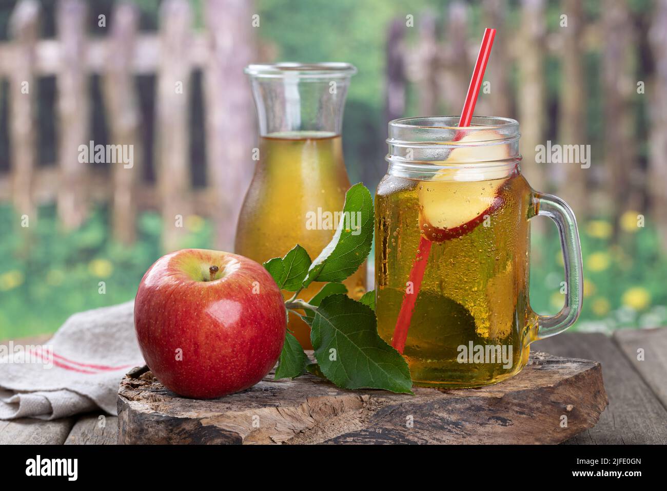 Vaso de jugo de manzana y manzana roja sobre un viejo bloque de madera con fondo rural Foto de stock