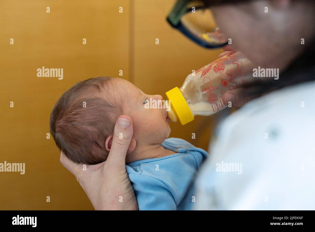Mujer joven que alimenta a un bebé prematuro recién nacido con un biberón de lactancia Foto de stock
