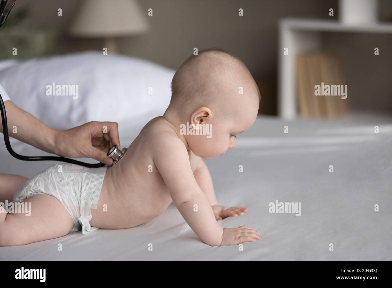El estetoscopio del uso del pediatra que examina la salud del bebé lindo en pañal Foto de stock