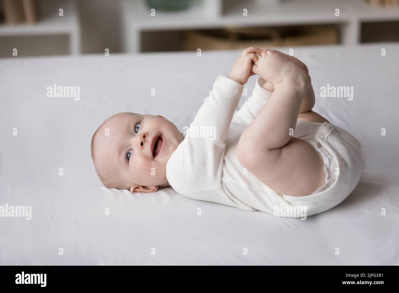 Bebé sonriente en el pelele y pañal acostado en la cama, primer plano Foto de stock