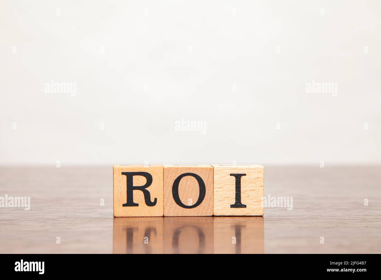 Carácter ROI. Retorno de la inversión. Retorno de la inversión. Escrito en tres bloques de madera. Letras negras. Fondo de mesa de madera. Foto de stock