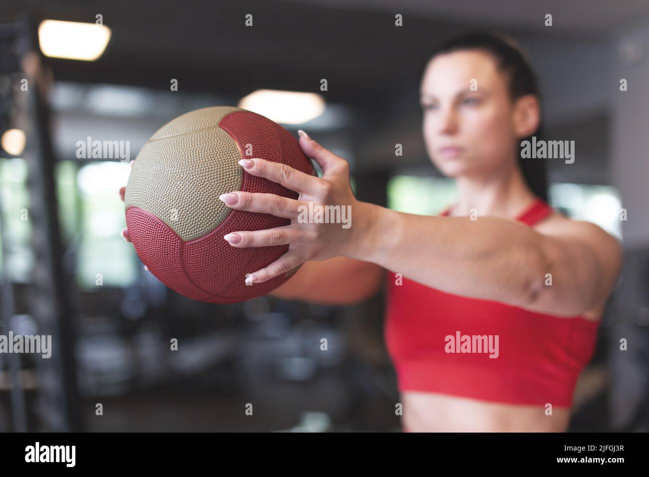 Mujer caucásica joven sosteniendo balón medicinal en el gimnasio Foto de stock