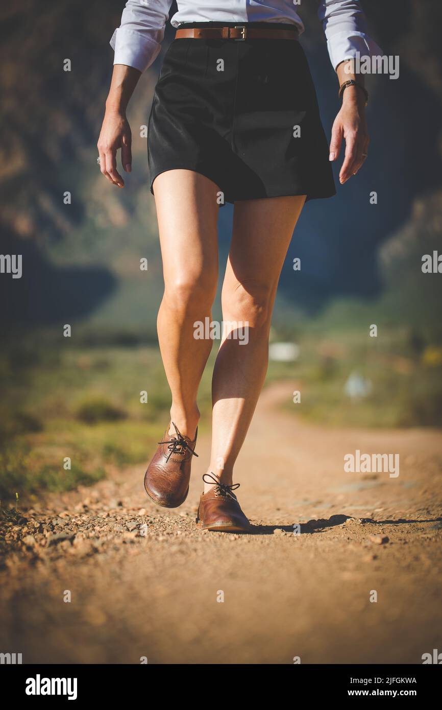 La parte baja de una joven con falda negra y zapatos marrones caminando por  un camino Fotografía de stock - Alamy