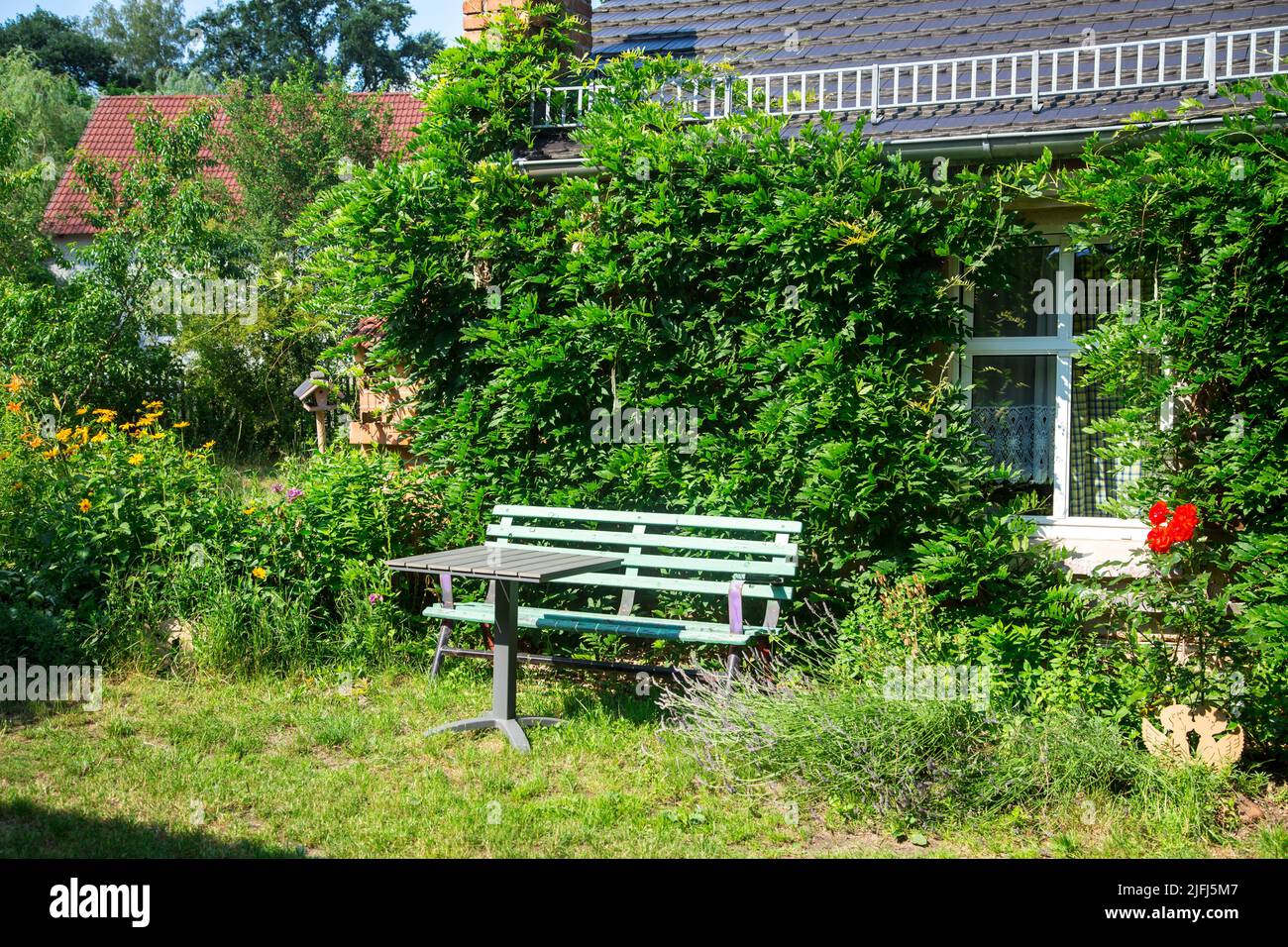 Banco verde frente a una antigua casa de ladrillo rojo, Lusatia, Alemania Foto de stock