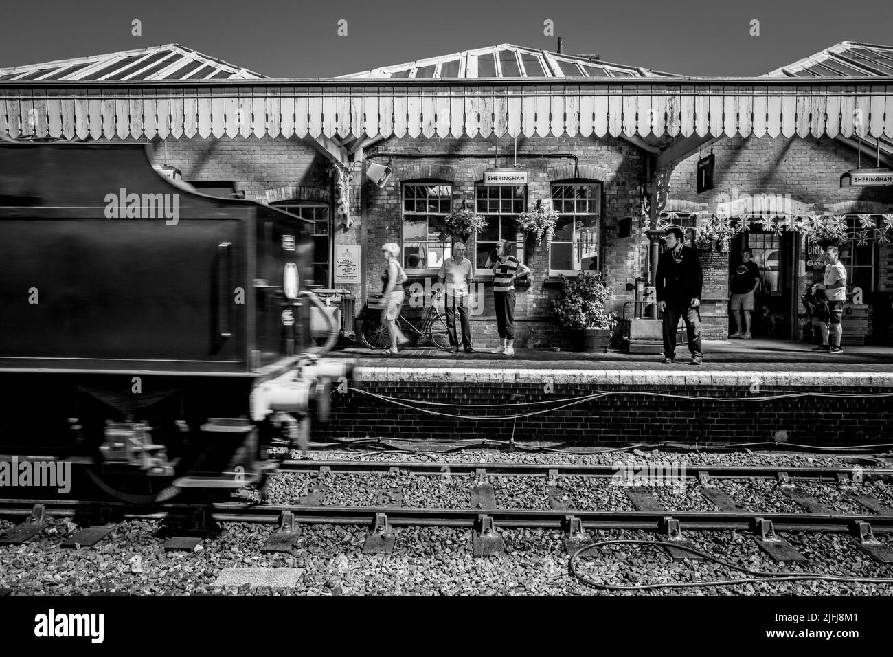 Pasajeros y turistas en la plataforma en la histórica estación ferroviaria de Sheringham que es parte de la línea ferroviaria North Norfolk. Foto de stock