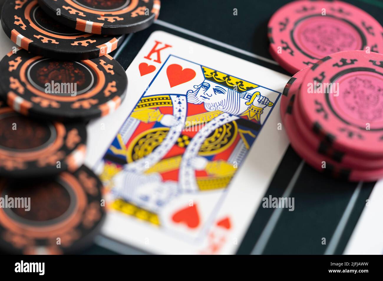 Primer plano de un rey de corazones jugando fichas de cartas y apuestas de póquer en una estera de póquer. Concepto - estrategia de poker, apuestas, adicción al juego Foto de stock