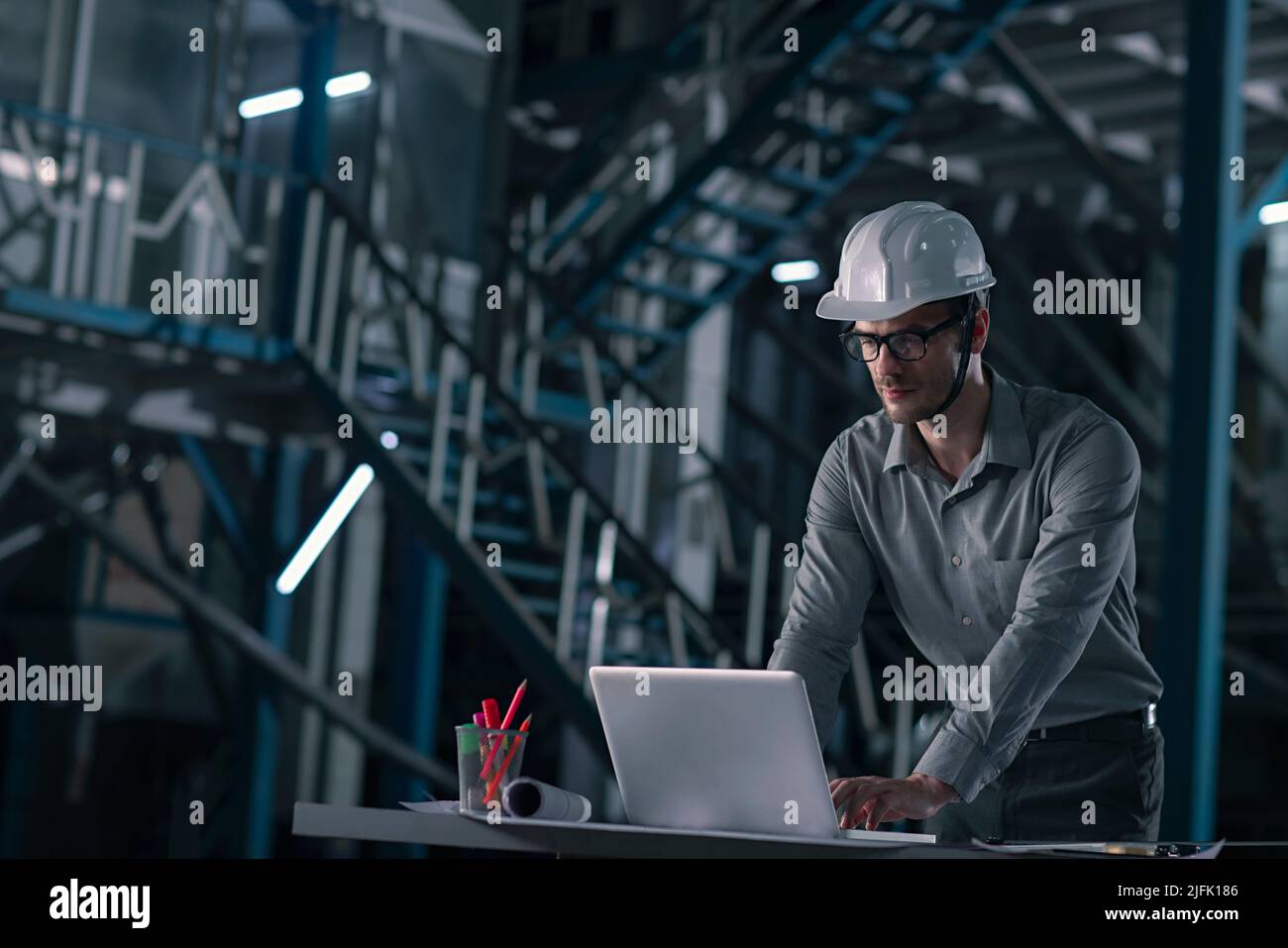Hombre adulto medio trabajando en el portátil en la fábrica Foto de stock