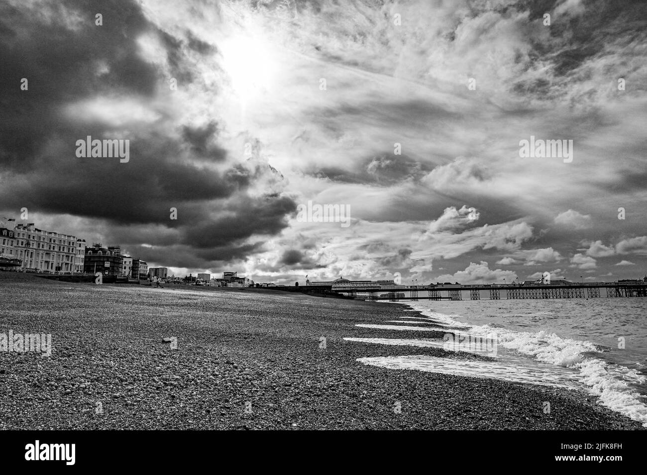 Brighton , Sussex , Inglaterra Reino Unido - Oscuras nubes sobre el paseo marítimo de Brighton y la playa con el sol tratando de romper a través Foto de stock