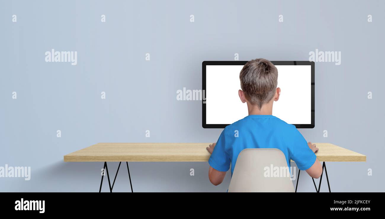 Niño aprender a codificar en el concepto de ordenador de sobremesa. Un chico con una camisa azul y la espalda girada. Copie el espacio a un lado. Pantalla de ordenador aislada para promoción de página Foto de stock