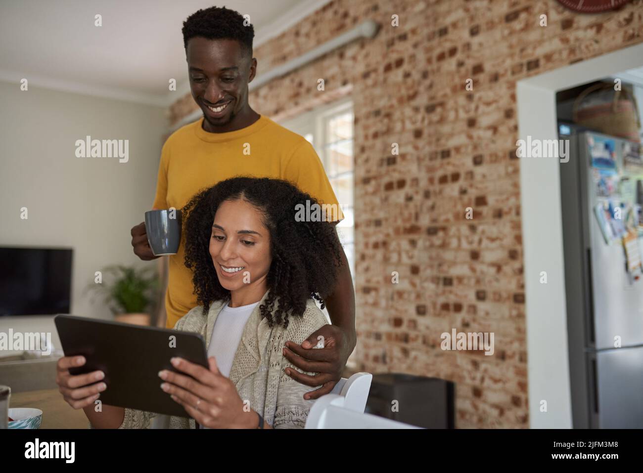 Sonriendo joven pareja multiétnica usando una tableta juntos en casa Foto de stock