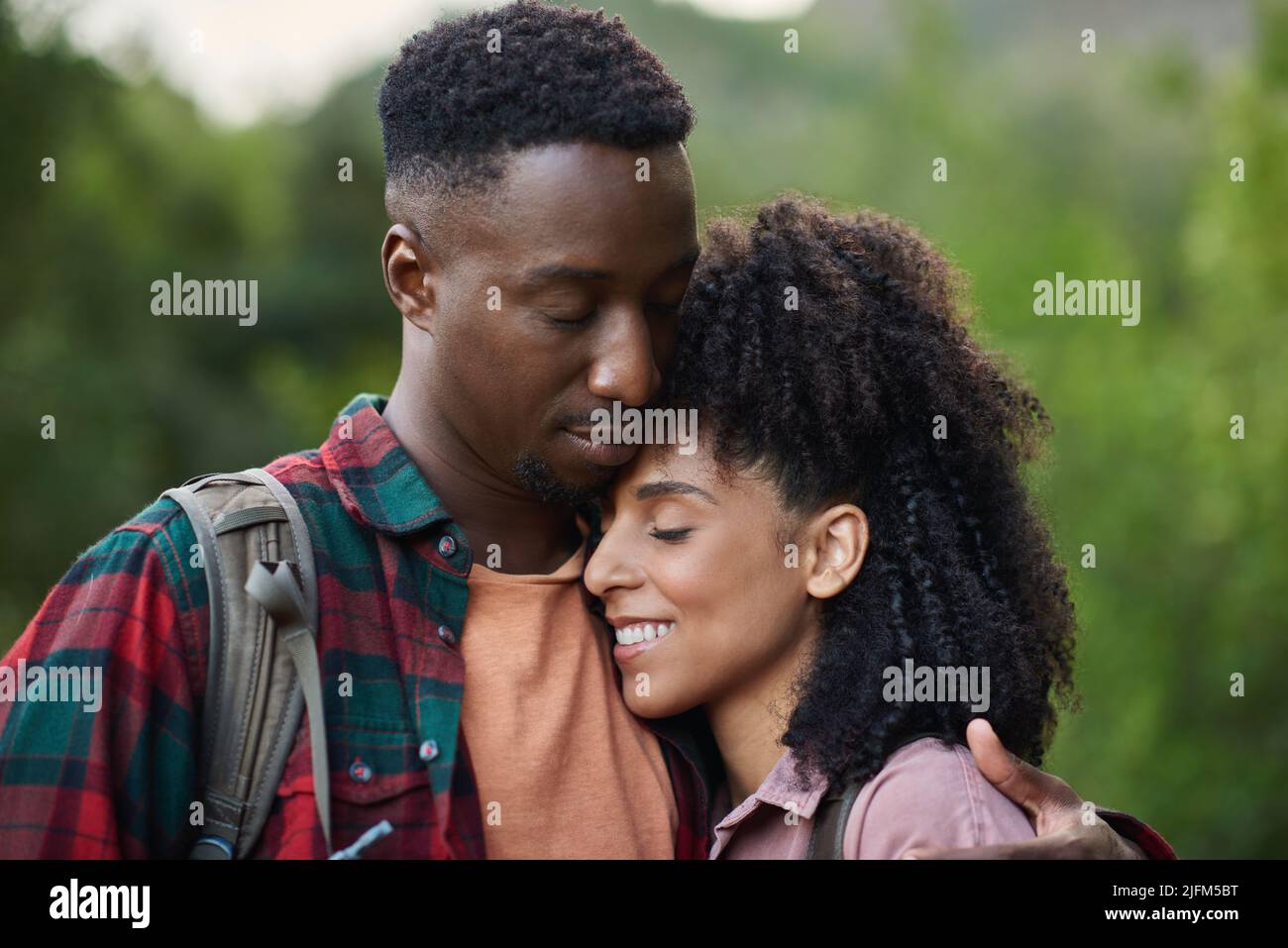 Cariñosa joven pareja multiétnica abrazándose durante un descanso de una caminata Foto de stock