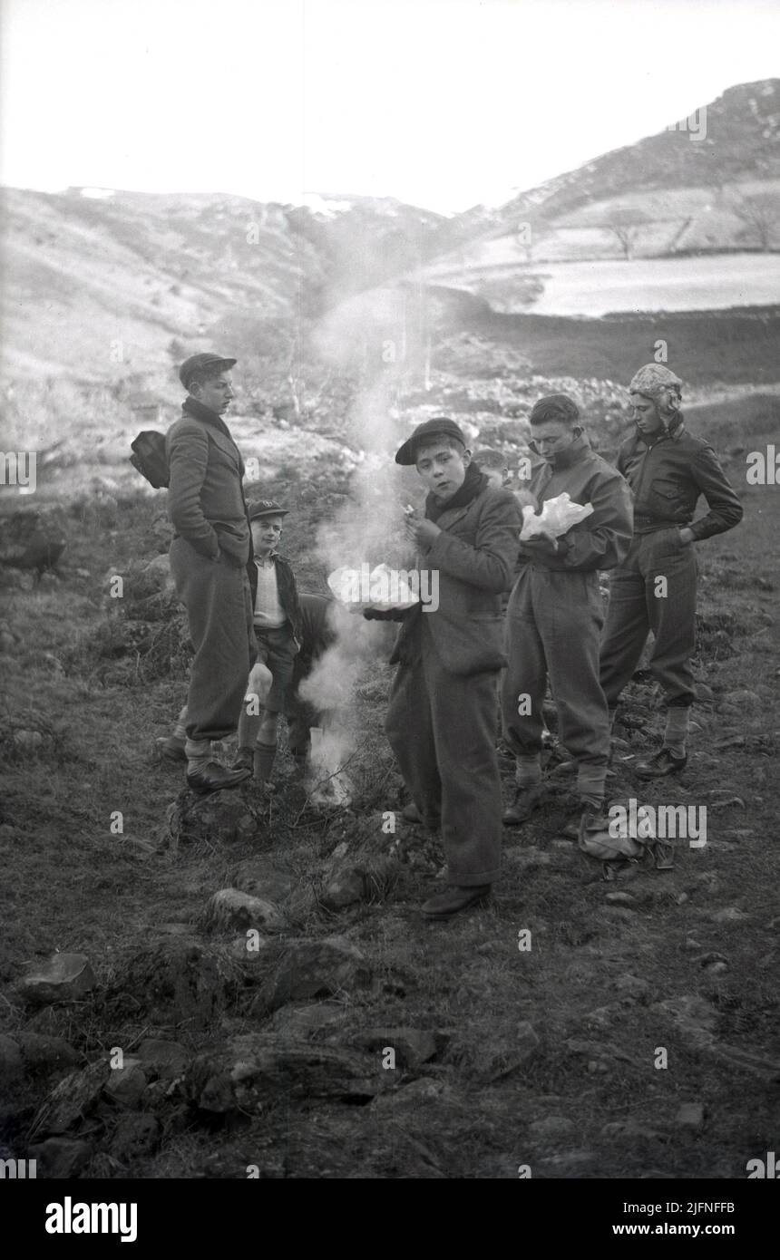 1952, histórico, campamento de fuego, los jóvenes en la ropa de la época cocinando, Lake District, Cumbria, Reino Unido. Foto de stock