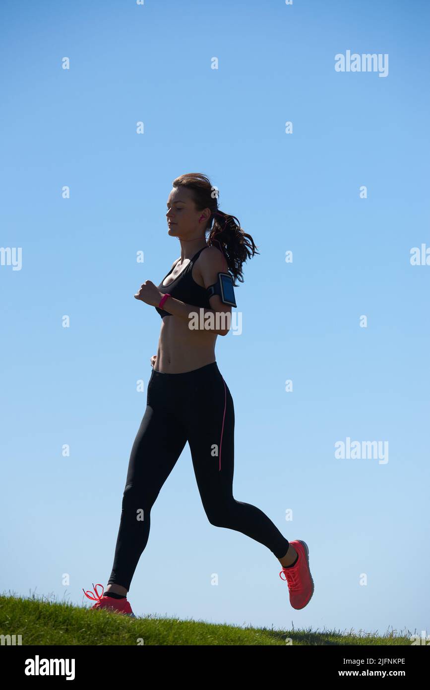 Es hora de ponerse en movimiento. Fotografía de una atractiva atleta joven haciendo ejercicio al aire libre. Foto de stock