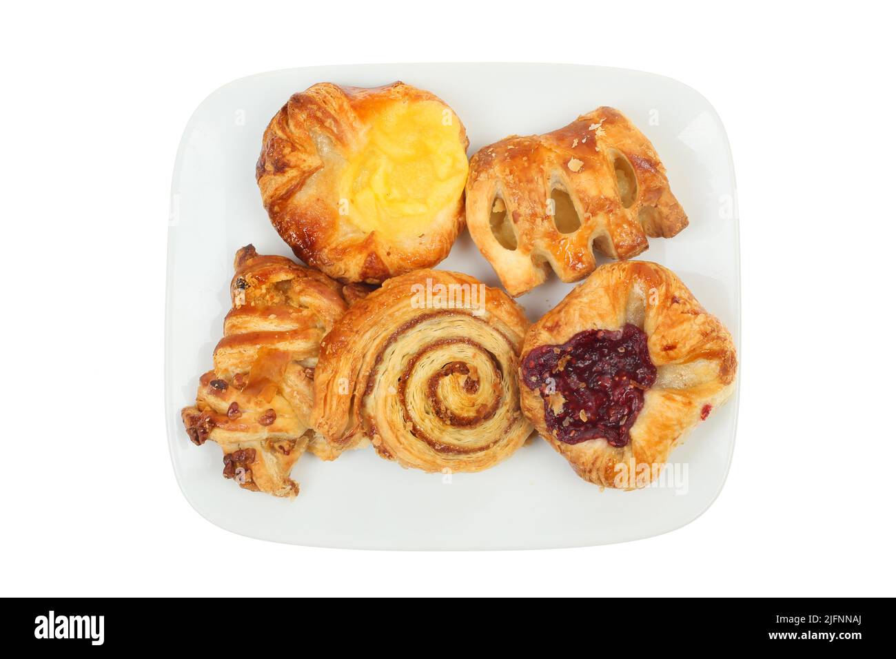 Selección de mini pasteles daneses en un plato, vista superior, aislados contra el blanco Foto de stock