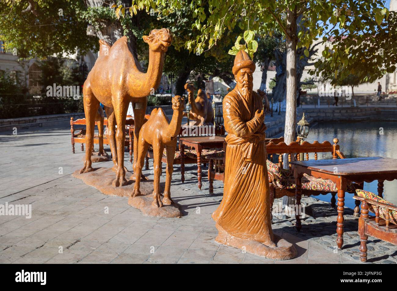 Bujara, Uzbekistán - Octubre, 2016: Escultura de camaleador y caravana de camellos cerca del estanque Lyabi Hauz en Bujara Foto de stock