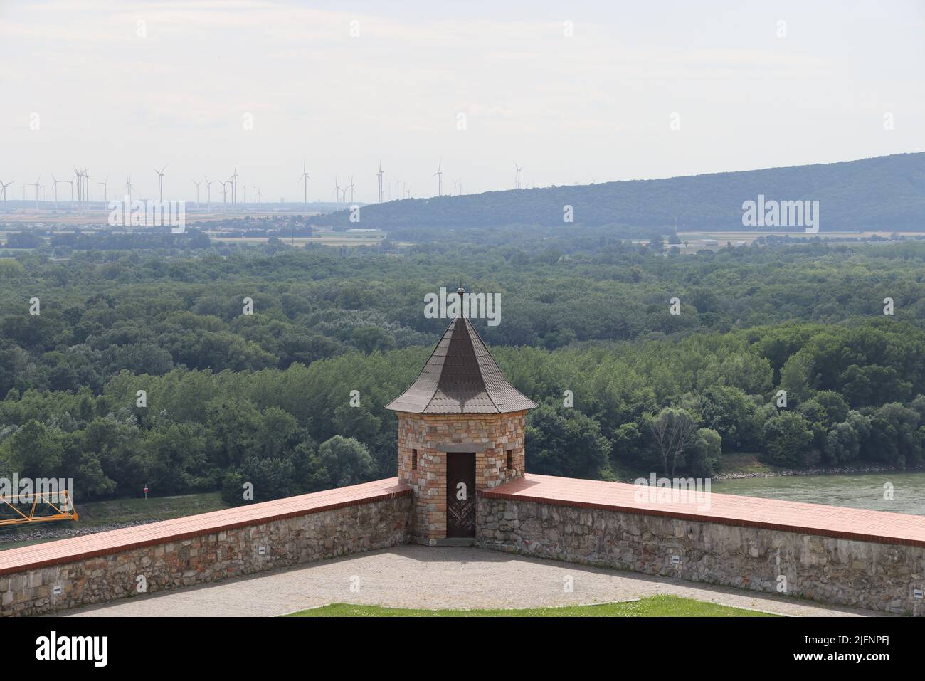 Vista desde el castillo de Bratislava en un grupo de muchos aerogeneradores en un paisaje montañoso verde cerca de la frontera Austria-Eslovaquia, con la torre del castillo Foto de stock