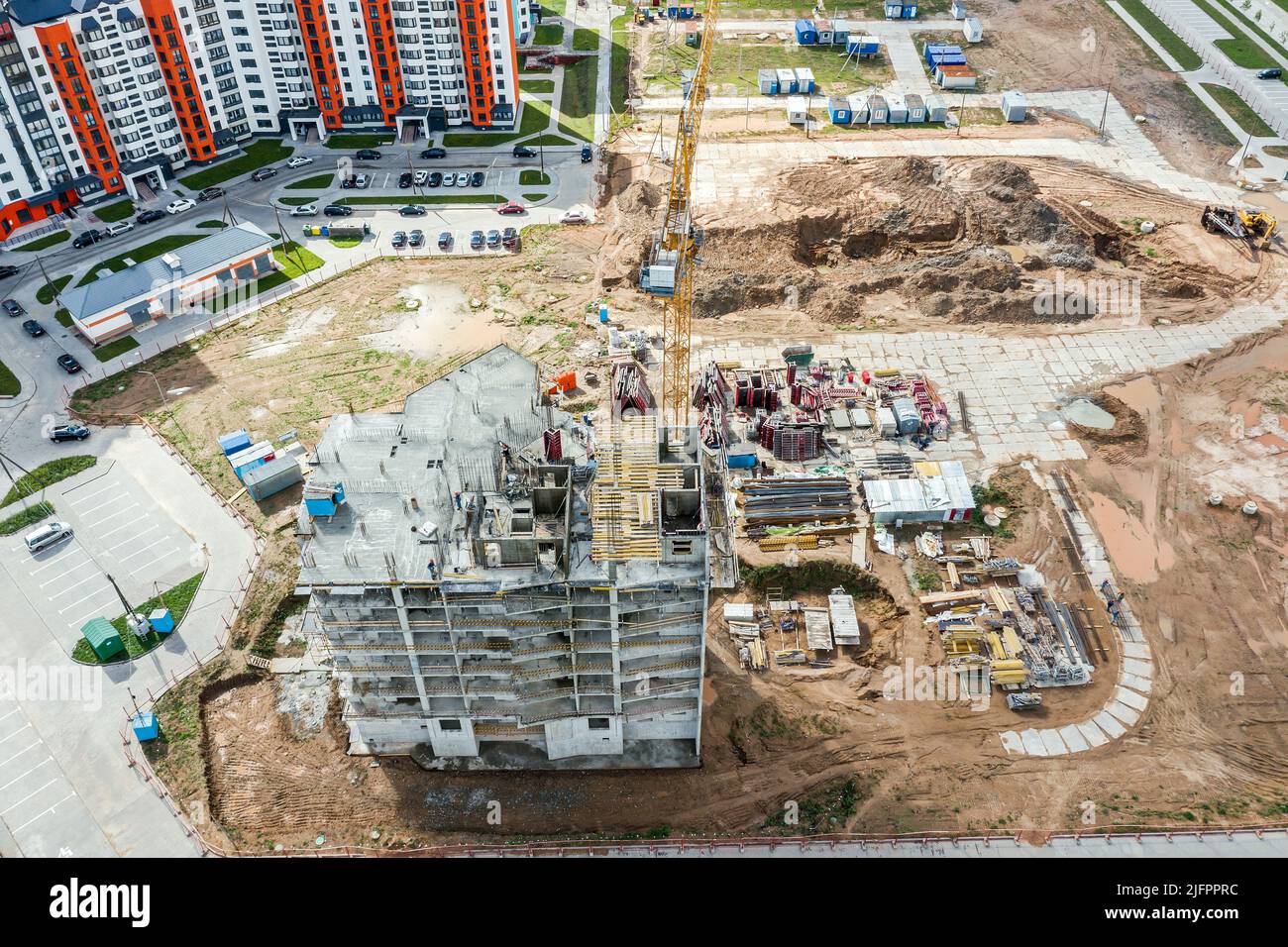 vista aérea del sitio de construcción en zona residencial con grúa amarilla y materiales de construcción Foto de stock