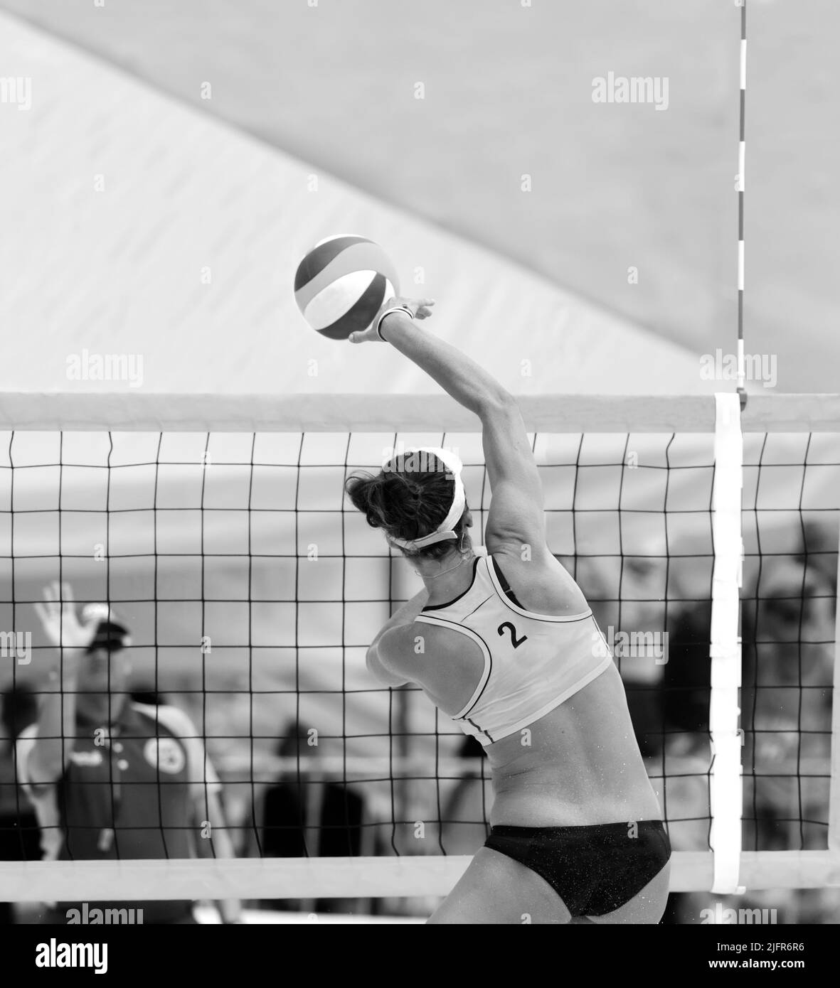 Un Jugador de Voleibol de Playa se está elevando para Spike the Ball en Formato de Imagen Vertical en Blanco y Negro Foto de stock