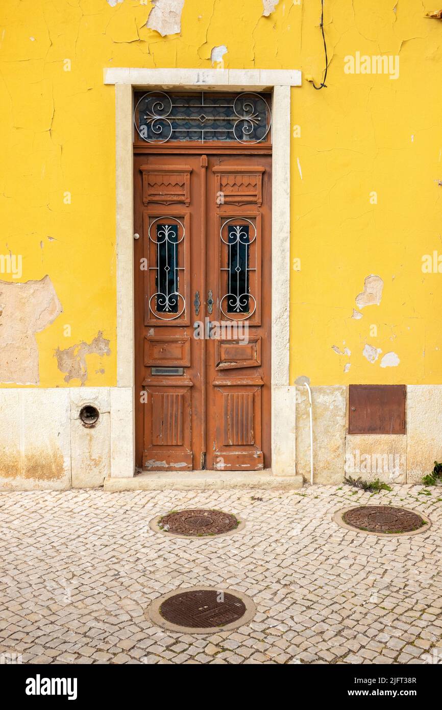 Puerta de Madera Vieja en una Casa Abandonada con pavimento Portugués (calcada portuguesa), en Portimao el Algarve, Portugal Foto de stock