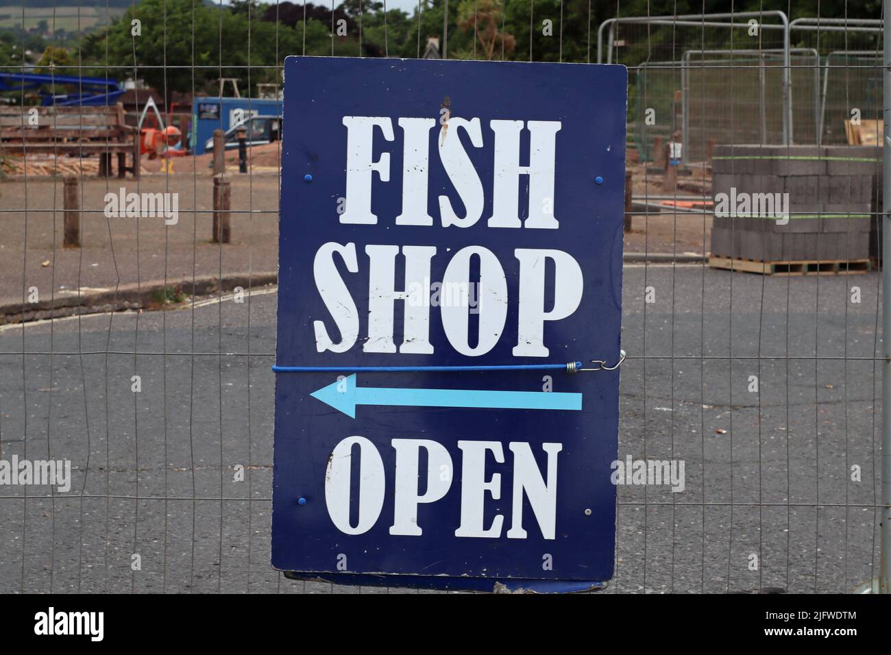 Un cartel temporal anunciando una tienda de pescado y chips en Sidmouth, en Devon. Se fija a una barandilla de alambre durante un proyecto de construcción Foto de stock