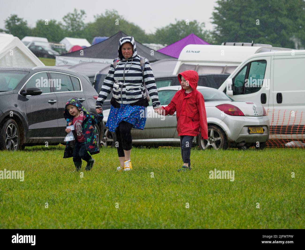Mamá con dos niños pequeños bajo la lluvia en el Launceston Steam & Vintage Rally, Cornwall, Reino Unido Foto de stock