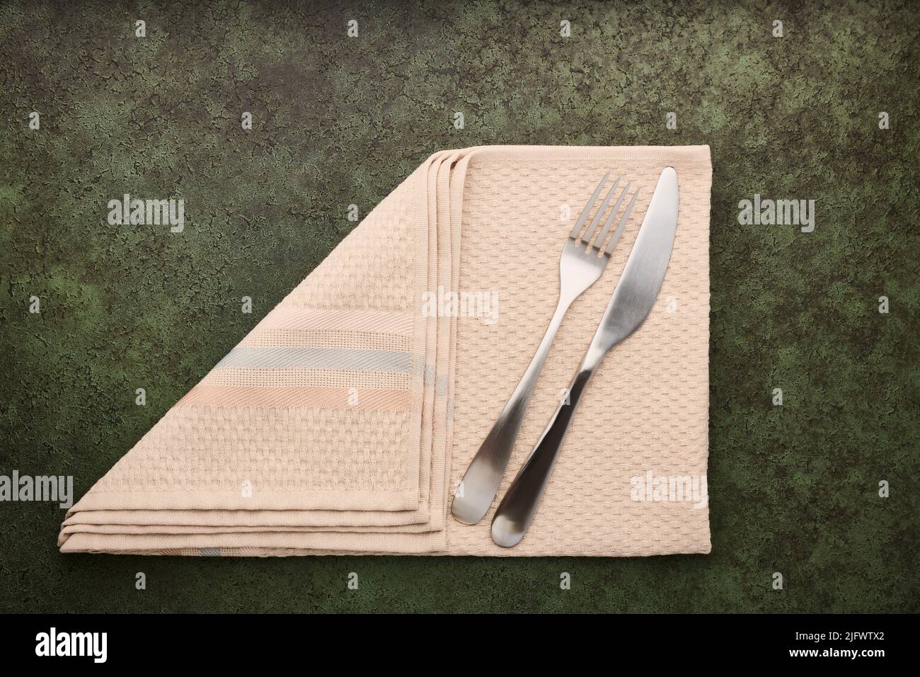 Tenedor de mesa y cuchillo acostado en servilleta doblada, concepto de servicio, primer plano con espacio para copias Foto de stock