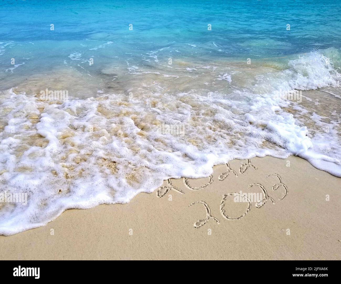 Vacaciones Año Nuevo 2023 texto en Bahamas arena de playa con olas tropicales del océano Foto de stock