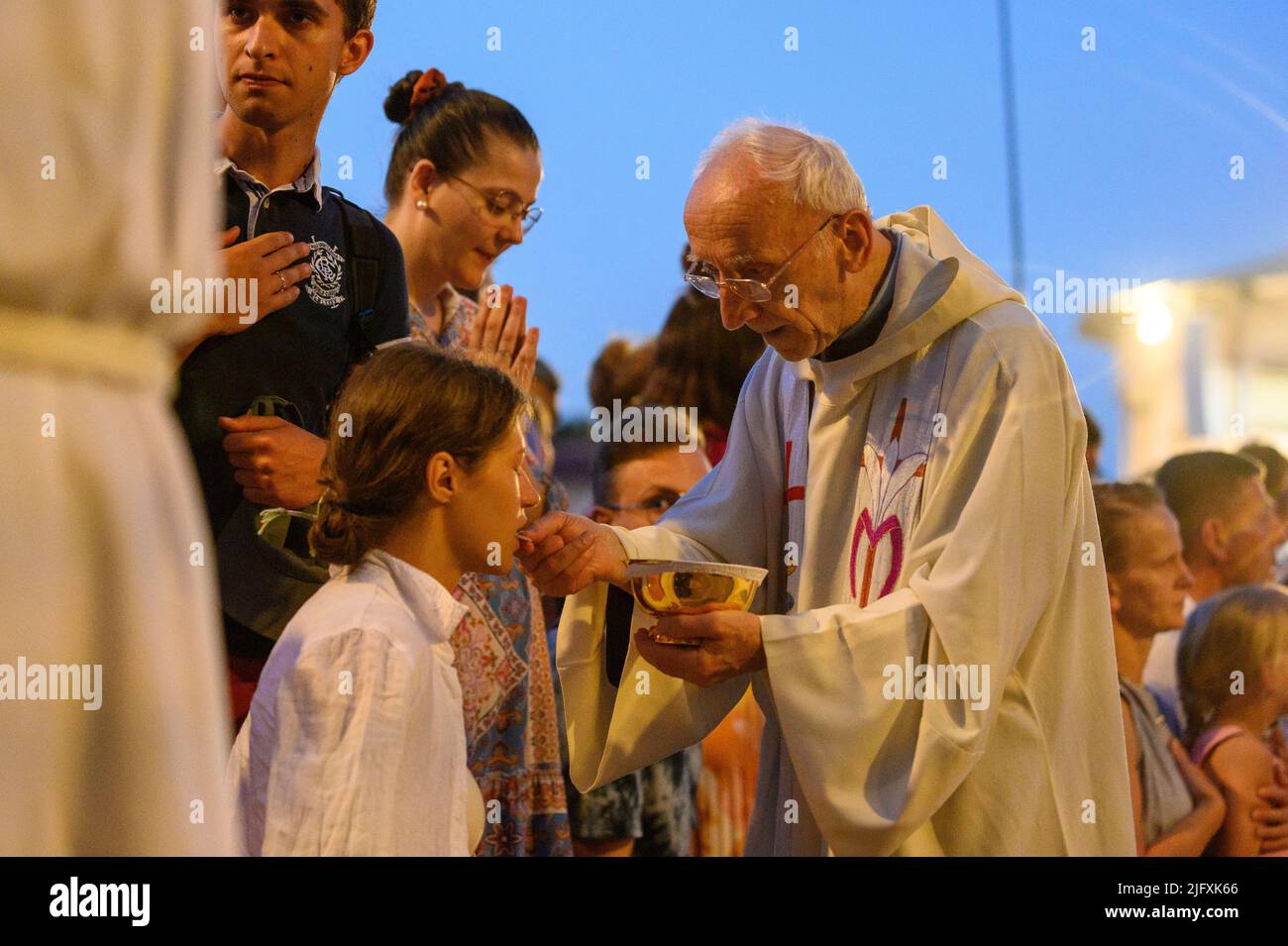 Un sacerdote anciano que da la Santa Comunión a los fieles. Foto de stock