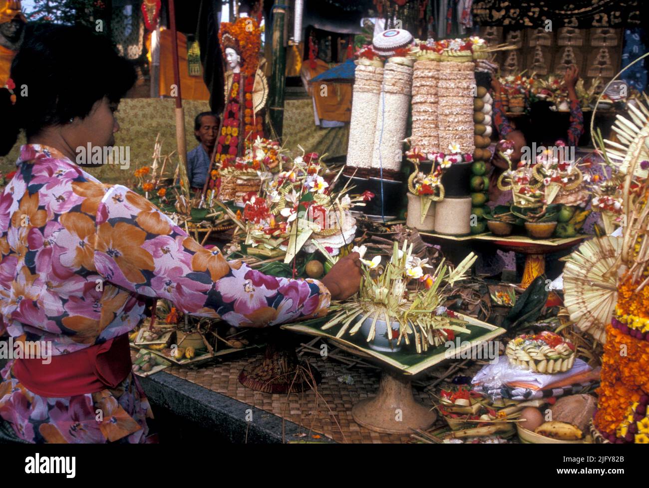 Mujer coloca regalos de flores y frutos en un templo en Bali, Indonesia Foto de stock