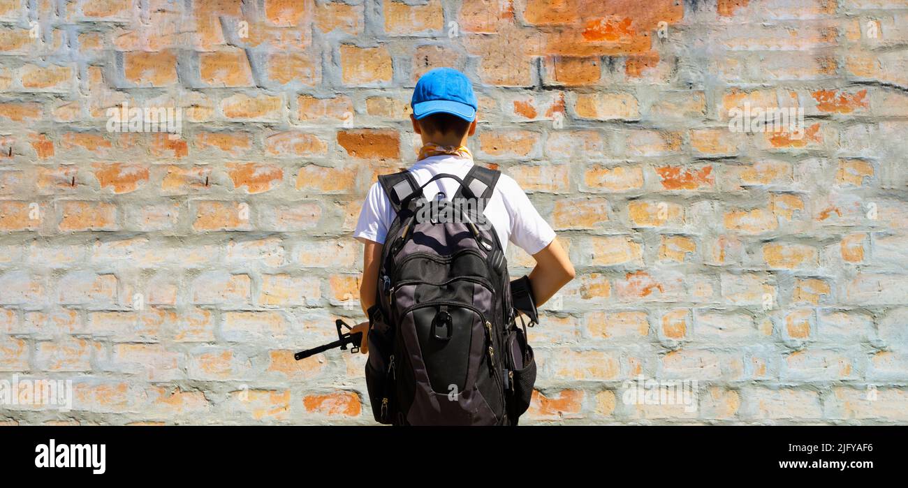 Un joven que llevaba un rifle y se enfrentaba a una pared. Segunda enmienda y el concepto de tirador de la escuela. Foto de stock