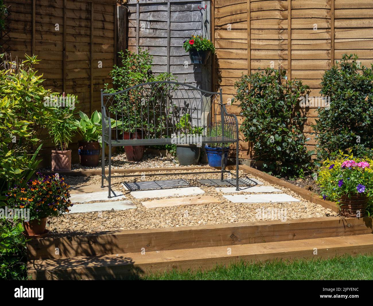 Área de patio creada con traviesas de madera y un relleno de grava, en un jardín suburbano, Northampton, Reino Unido Foto de stock