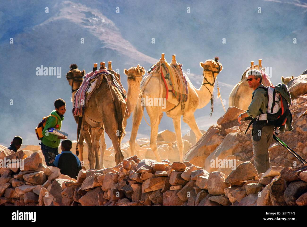 Turista, niños beduinos y camellos descendiendo el Monte Sinaí al amanecer - Península del Sinaí, Egipto Foto de stock