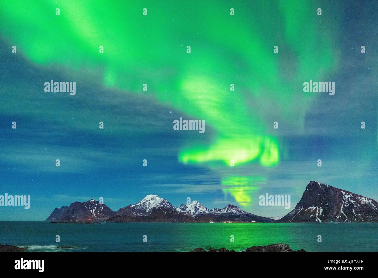 Luces verdes brillantes de Aurora Borealis (aurora boreal) que se reflejan en el mar, Myrland, Leknes, Vestvagoy, Lofoten Islas, Noruega, Escandinavia Foto de stock