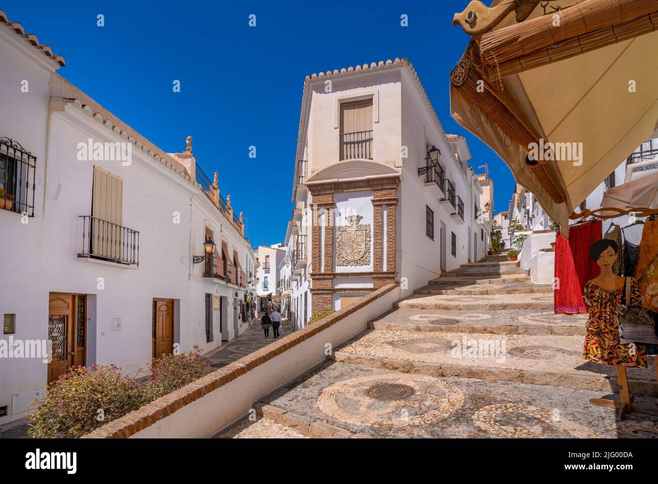 Vista de casas encaladas y tienda de ropa en calle estrecha, Frigiliana, provincia de Málaga, Andalucía, España, Mediterráneo, Europa Foto de stock