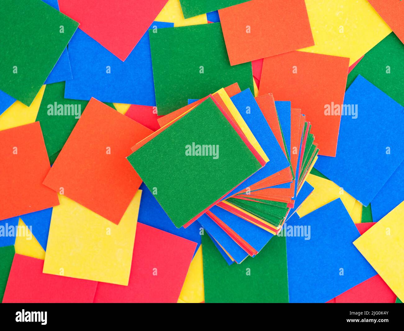 Trozos de papel multicolor apilados sobre un fondo de trozos de papel rectangulares multicolor. Fotograma completo. Foto de stock