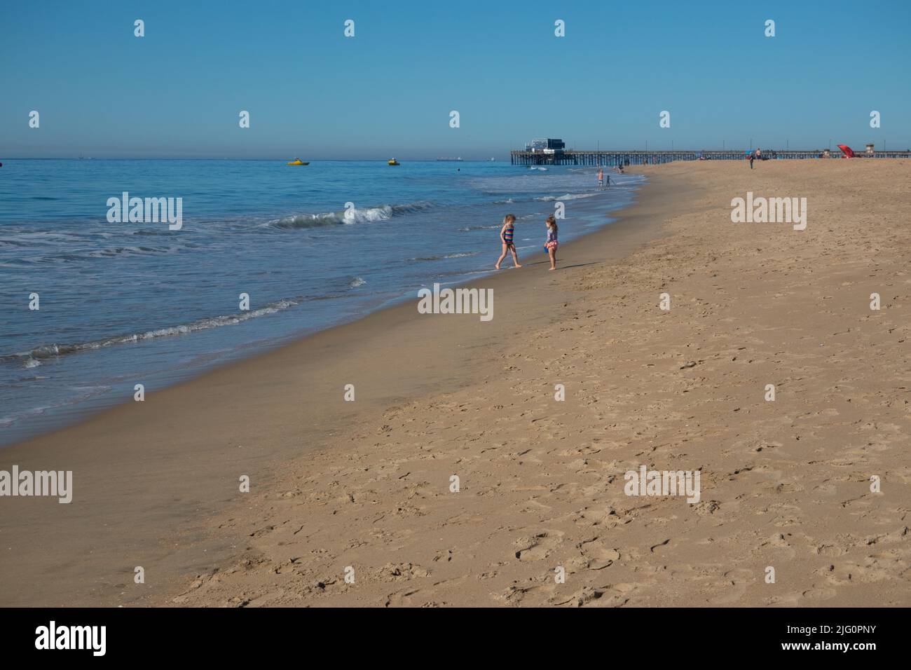 Los niños y el muelle y un largo tramo de playa de arena en Balboa Peninsula Beach Newport Beach, California, Estados Unidos Foto de stock