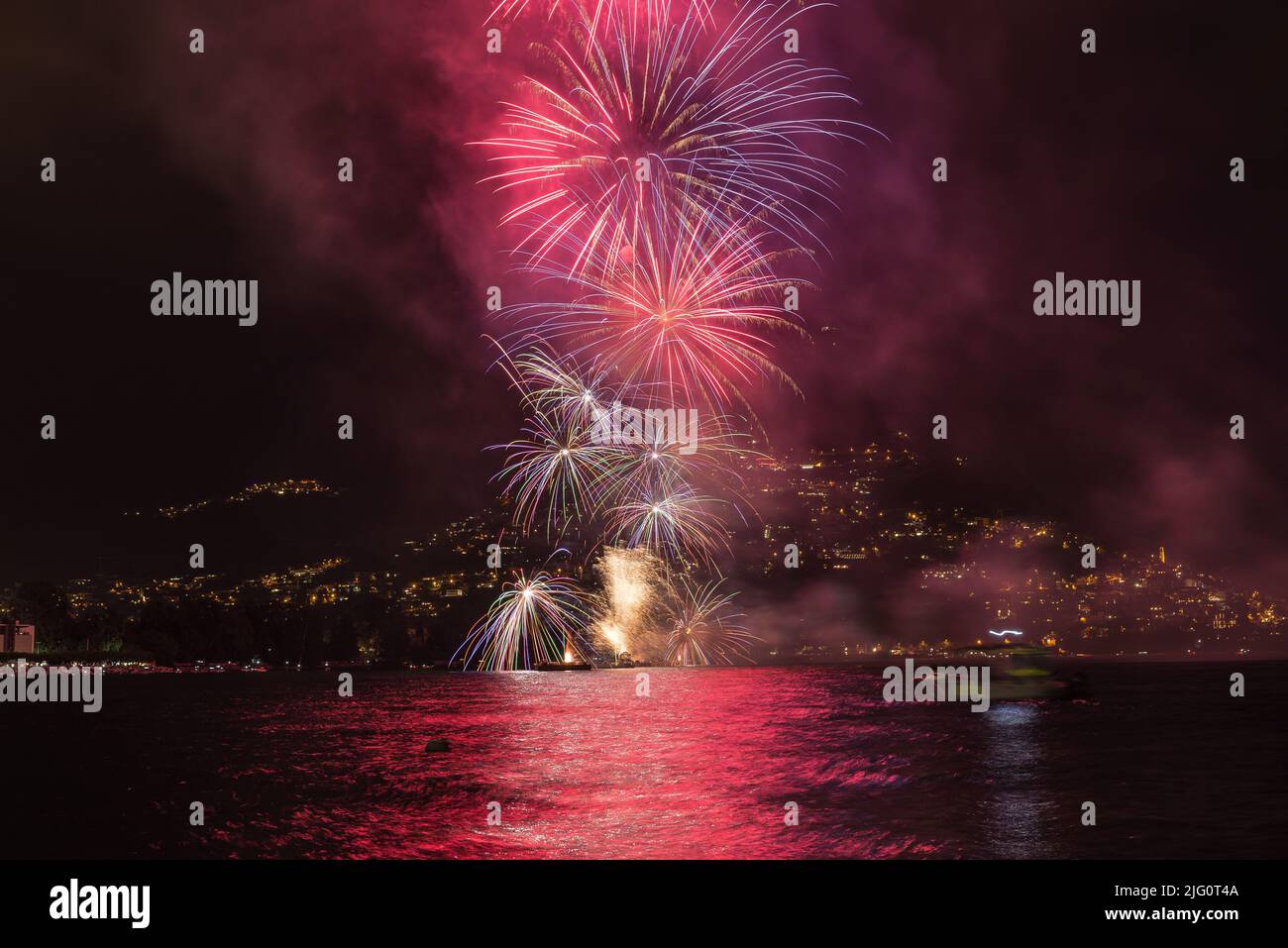 Fuegos artificiales por la noche sobre el lago. Día Nacional Suizo del 1st de agosto en la ciudad de Lugano en el Lago Lugano con un espectáculo de fuegos artificiales. Concepto de turismo y ocio Foto de stock