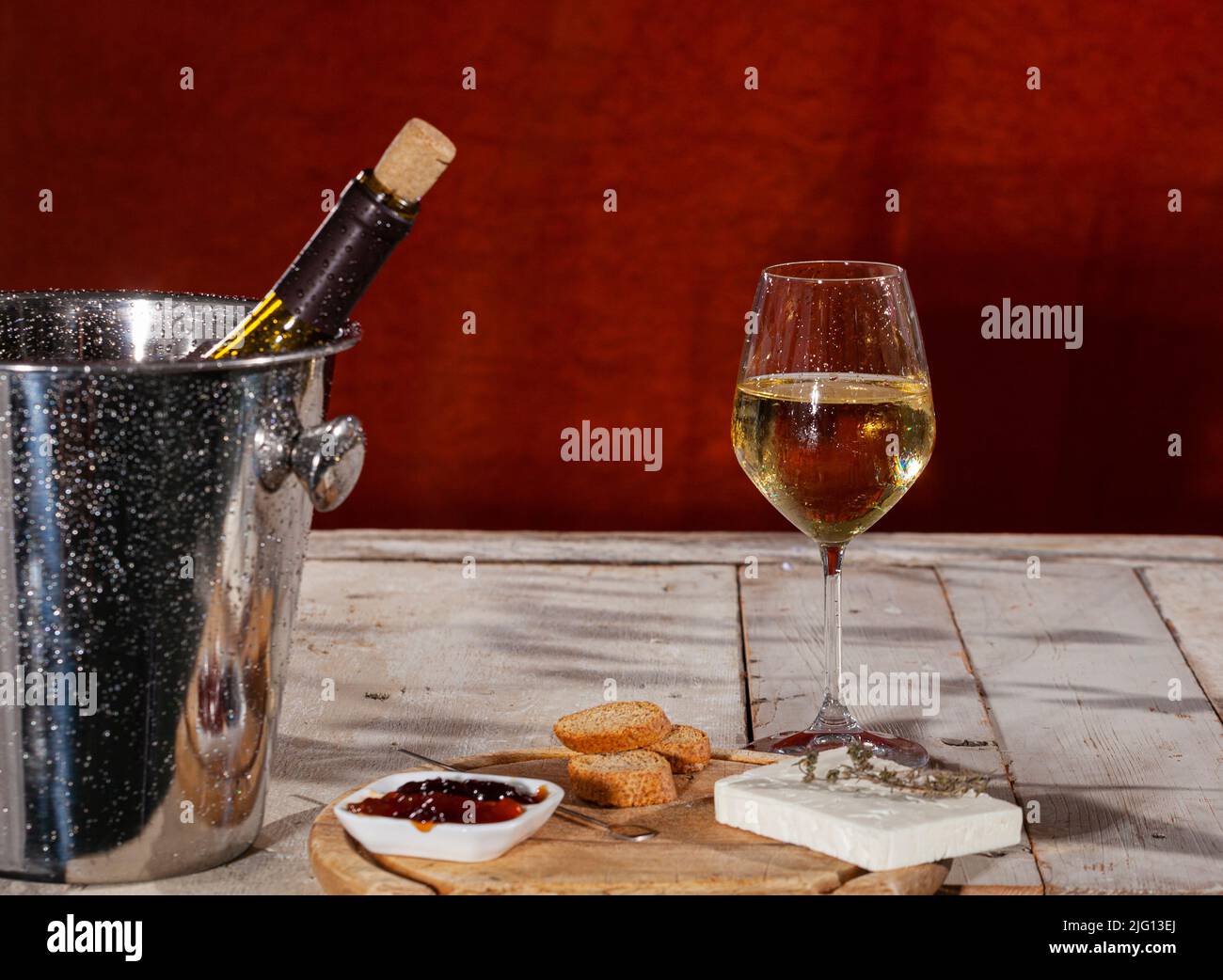 Delicioso aperitivo con tabla de queso Feta y mermelada servida con vino blanco fresco Foto de stock
