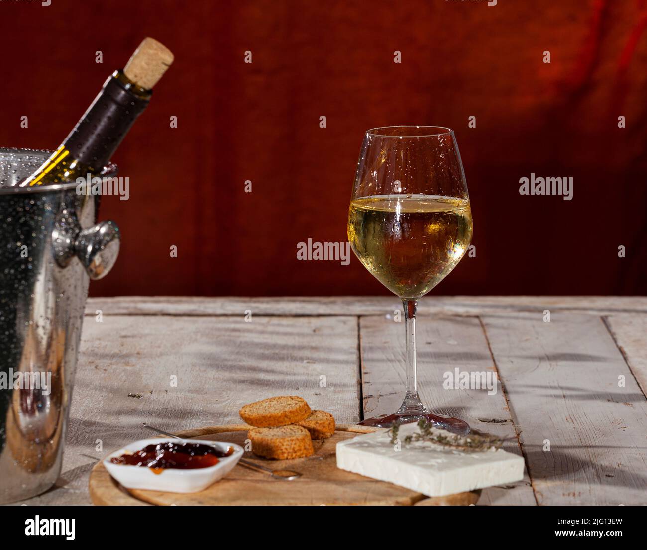 Delicioso aperitivo con tabla de queso Feta y mermelada servida con vino blanco fresco Foto de stock