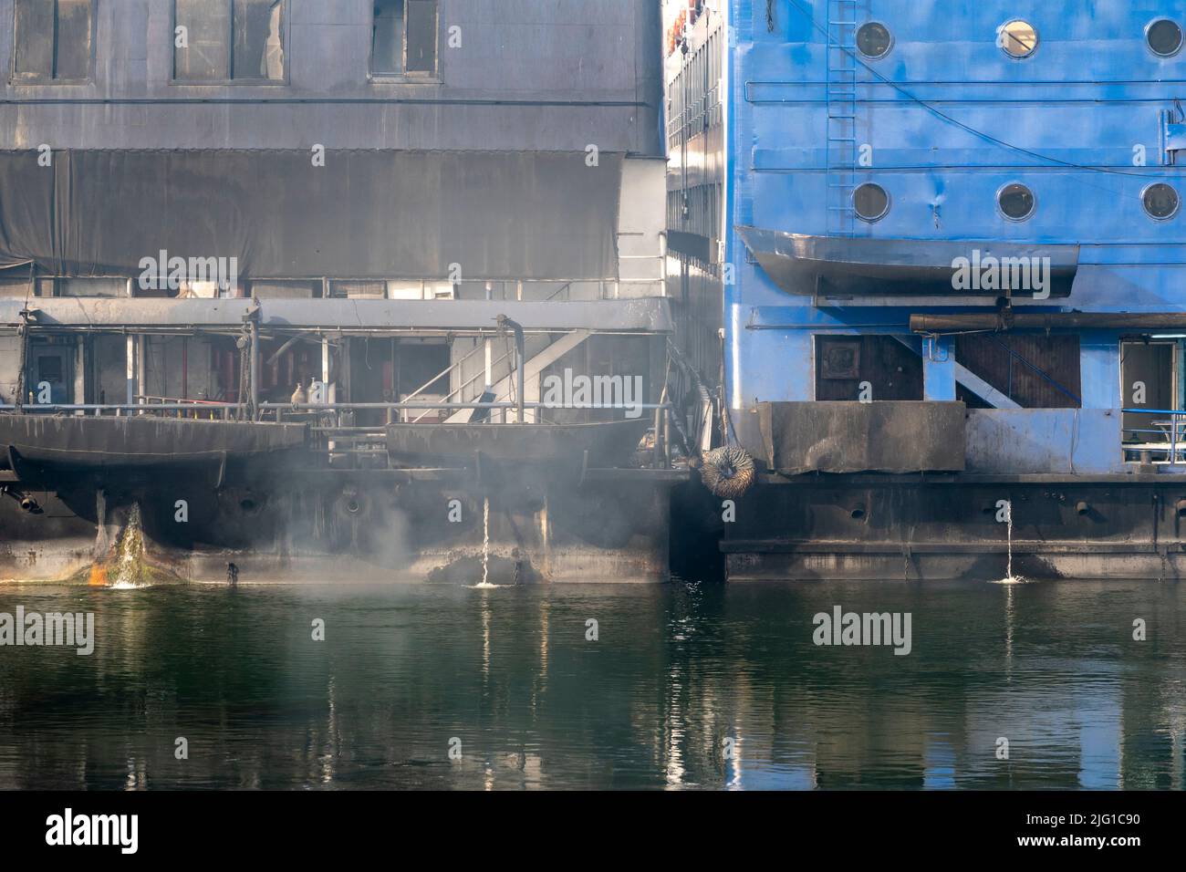 Dos barcos de crucero por el Nilo amarrados lado a lado con humos y reflejos en el río Nilo Foto de stock