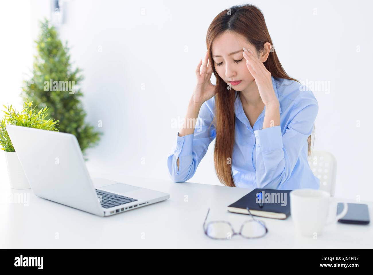 Mujer de negocios asiática estresada y con dolor de cabeza que trabaja en la oficina Foto de stock